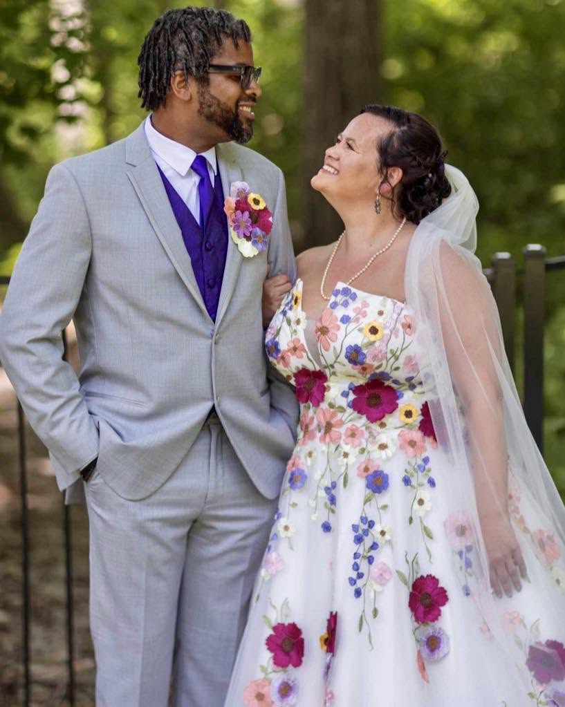 Real bride laughing with her groom outdoors in her handmade floral wedding dress